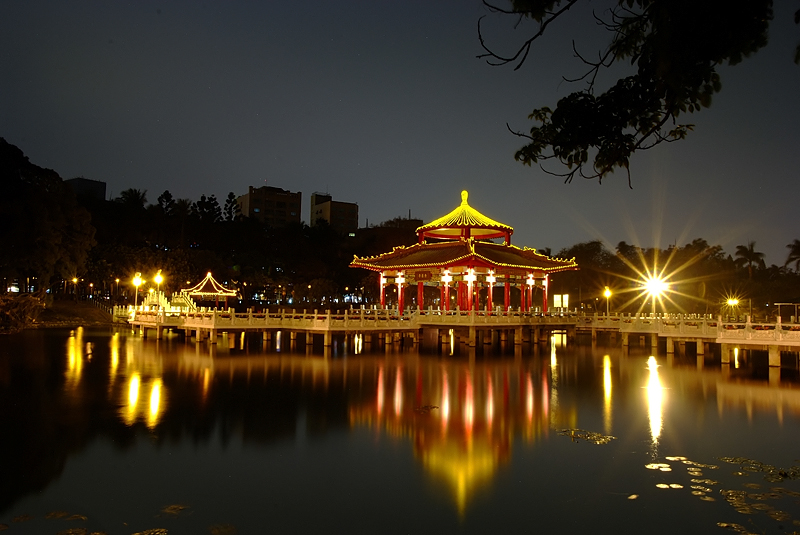 a temple with lit lights on a bridge over water