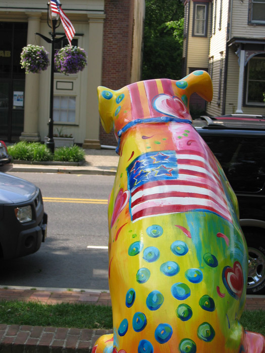 a brightly painted bear in front of a row of buildings