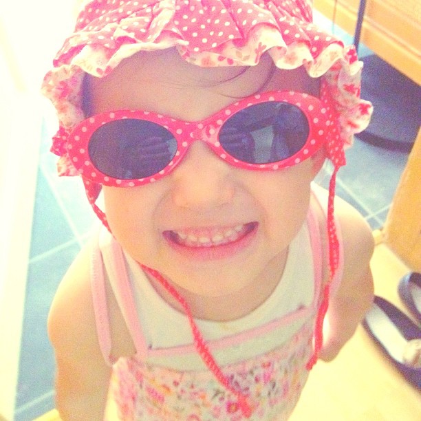 a little girl wearing pink sunglasses and a pink hat