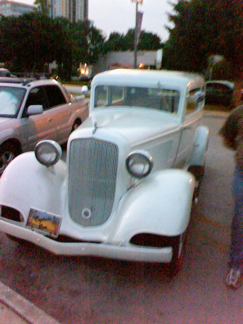 the old fashioned classic car is white and parked