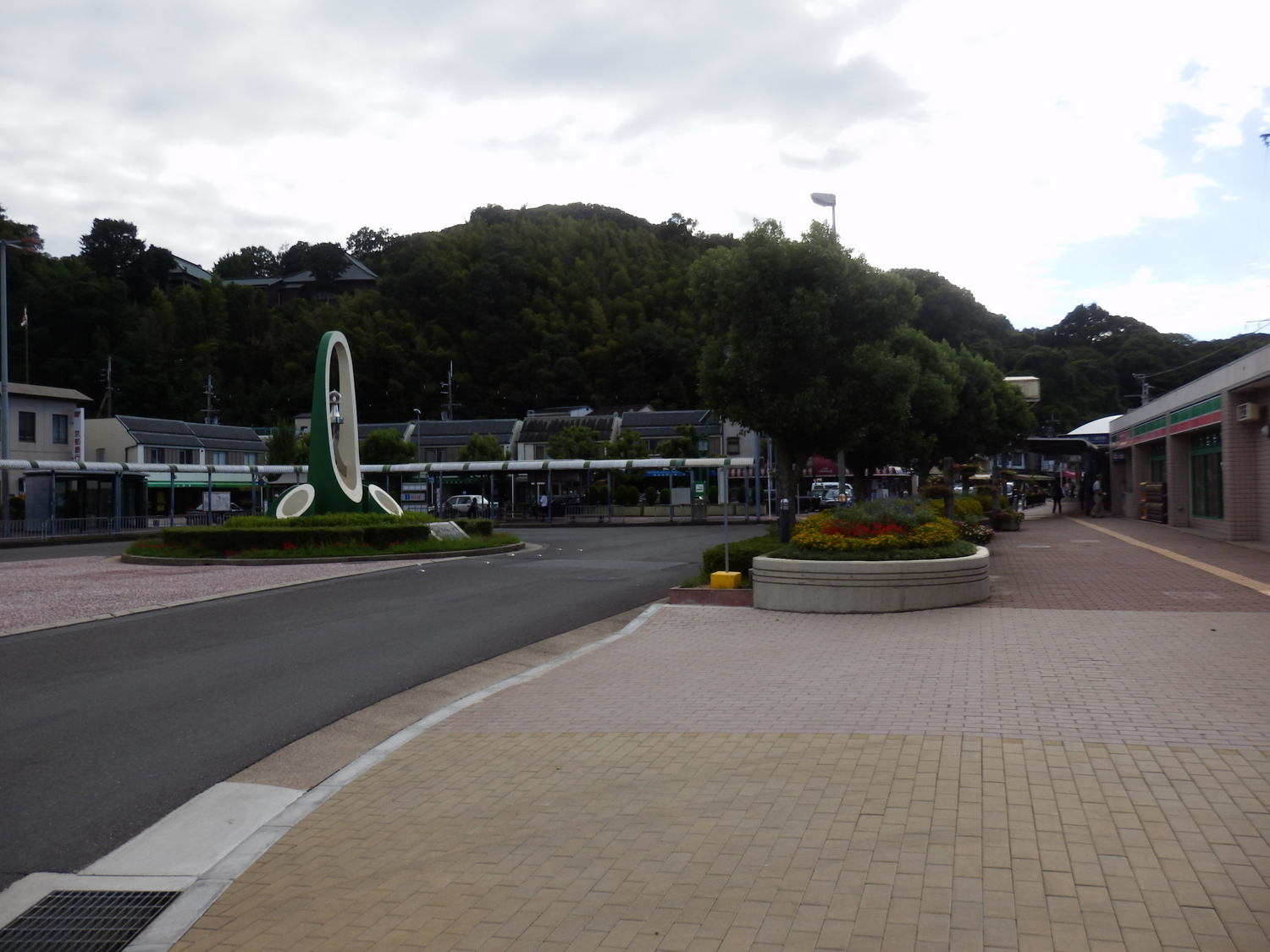 an empty city square with several flower beds, benches, and umbrellas