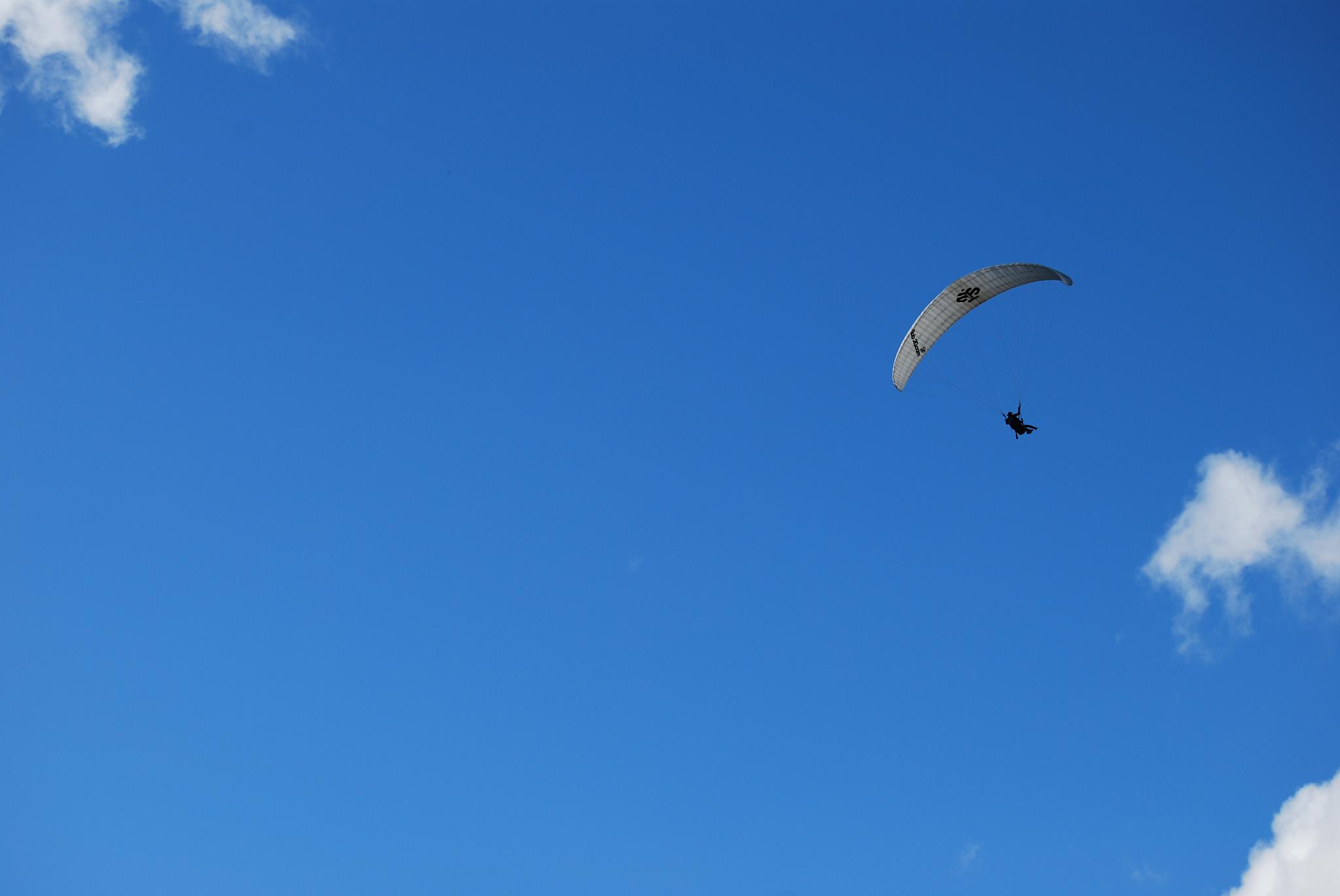 a parasailer flies through the blue sky with a propeller