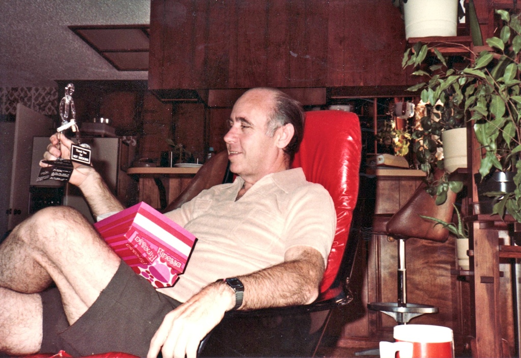 a man is sitting in a red chair holding up a book