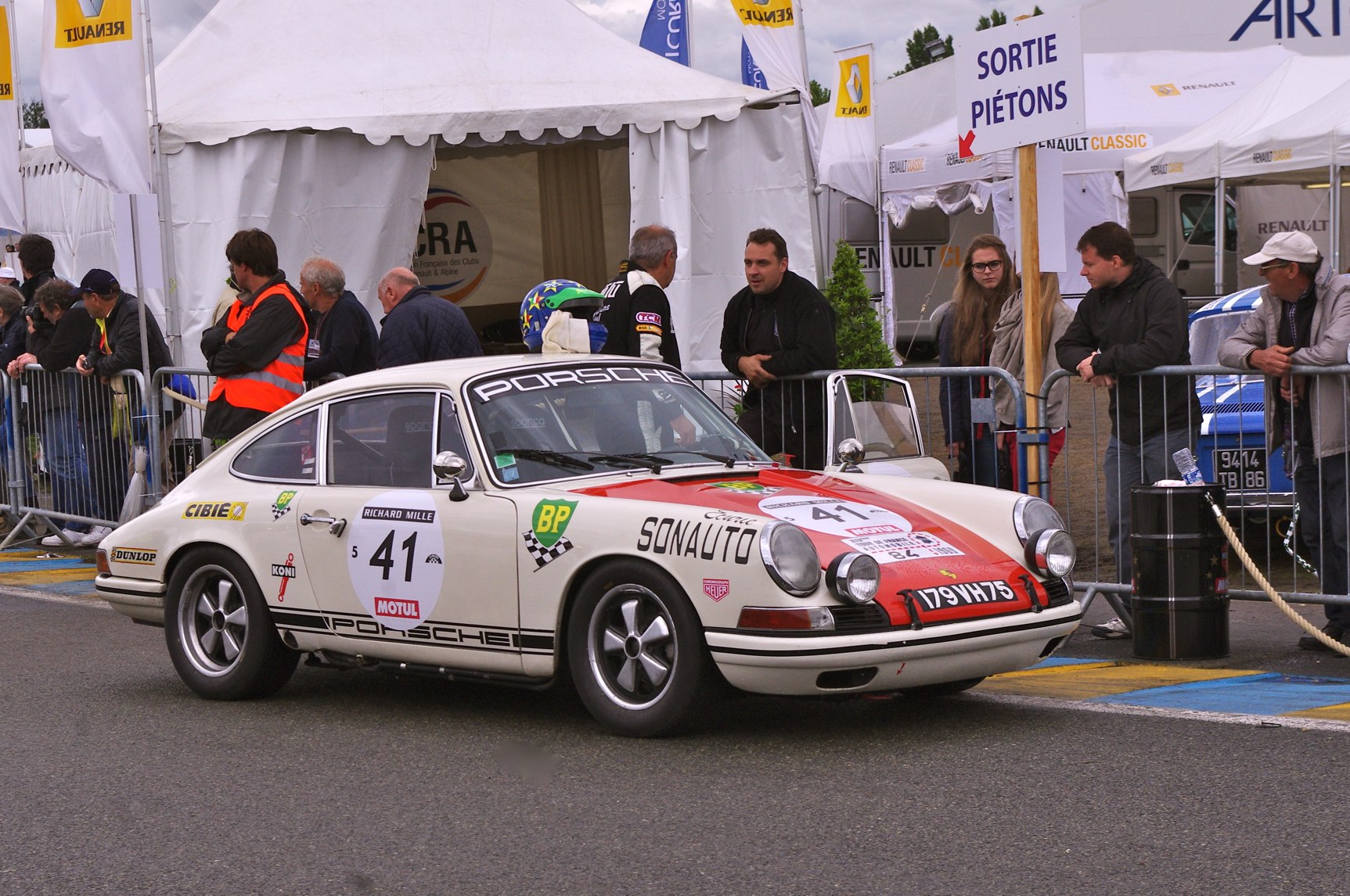 an old car with sticker decals on the side drives in front of an audience