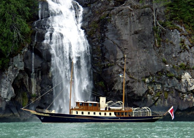 a boat in front of a waterfall and water coming from the rocks