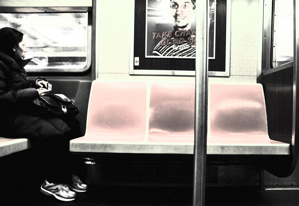 a person sitting on a subway looking at their cell phone
