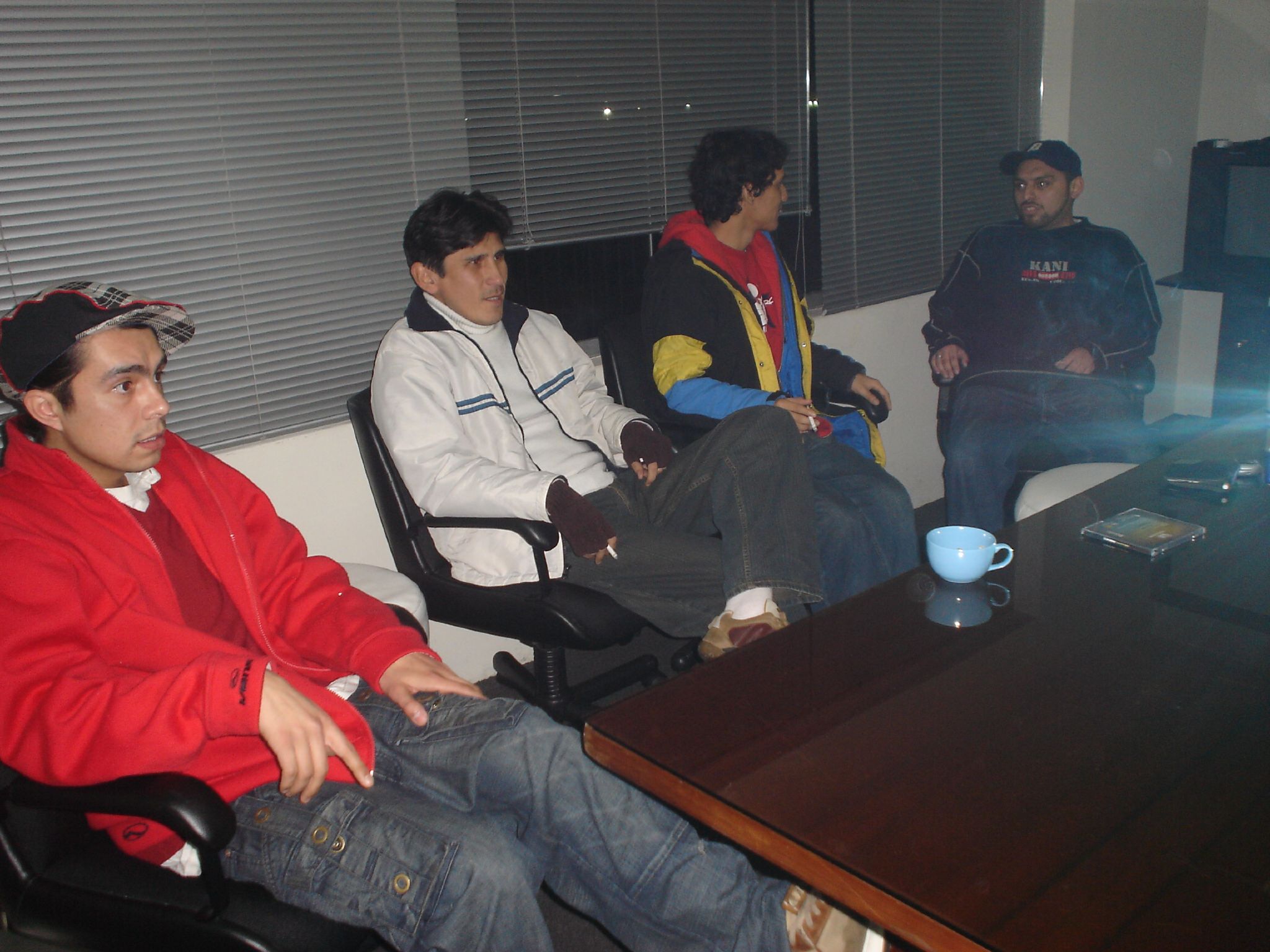 four men are sitting at a table playing wii