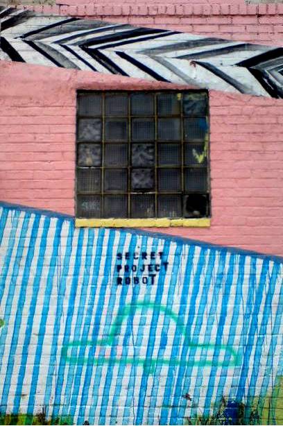 the building has graffiti on it and is next to a blue fence