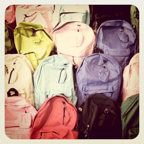 a bunch of colored backpacks all in a pile