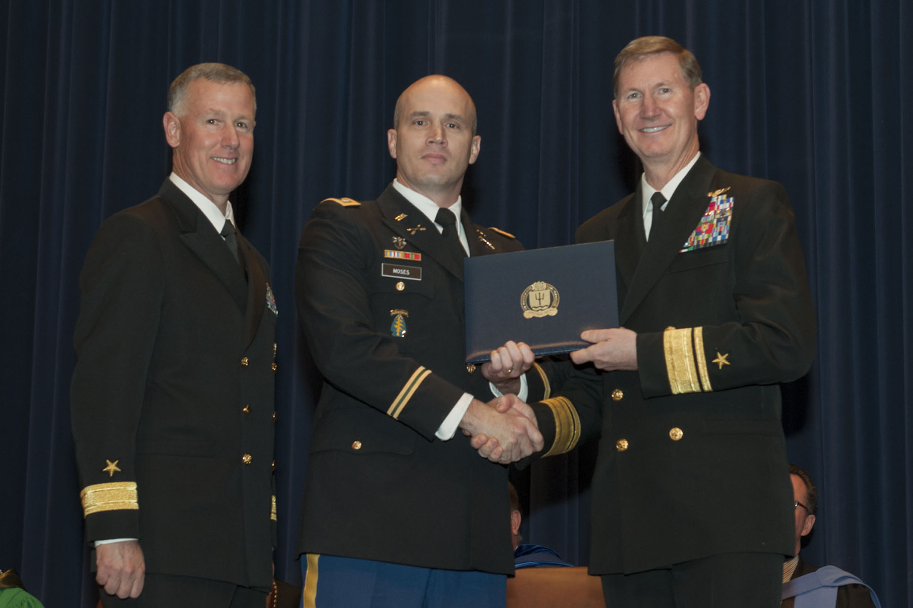 three men wearing military uniforms in front of a curtain