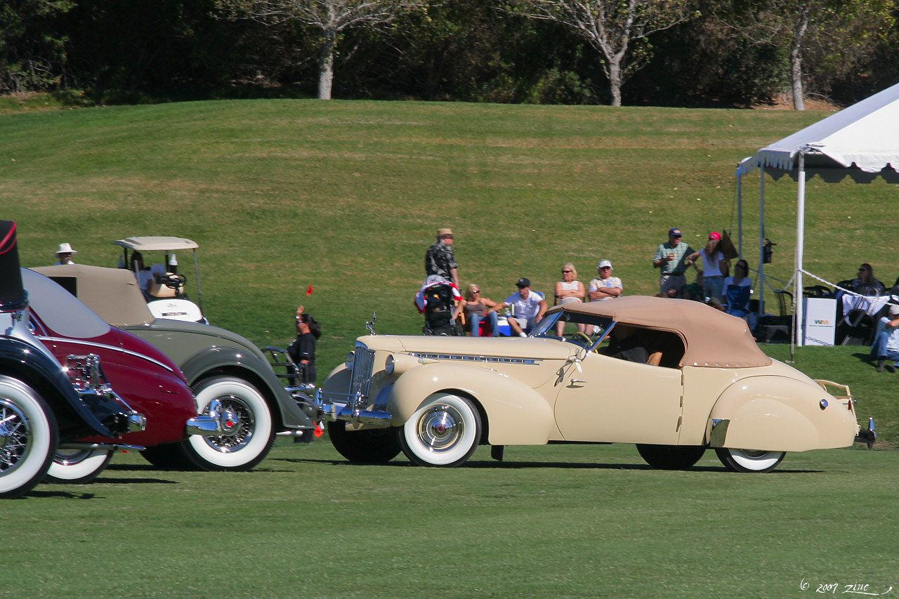 there are two antique cars driving on the green