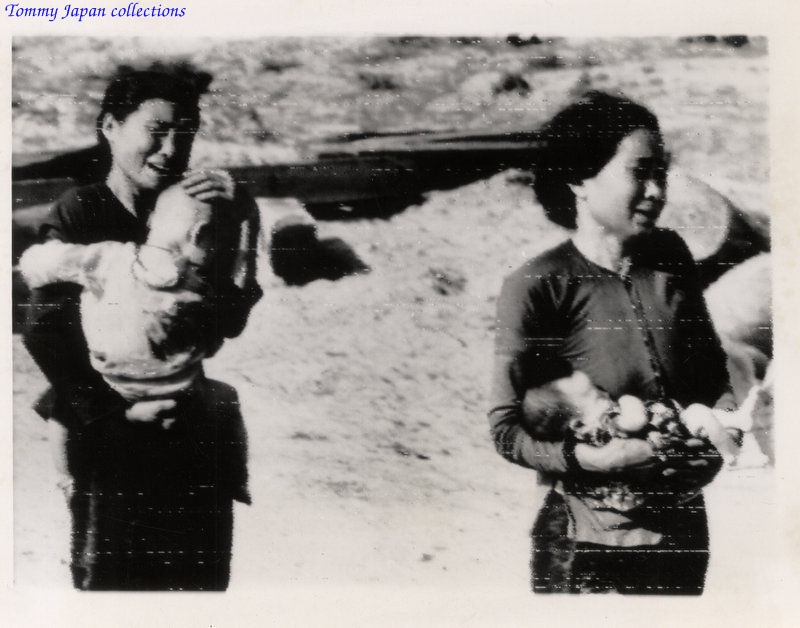 two people holding babys in their hands standing on a hill