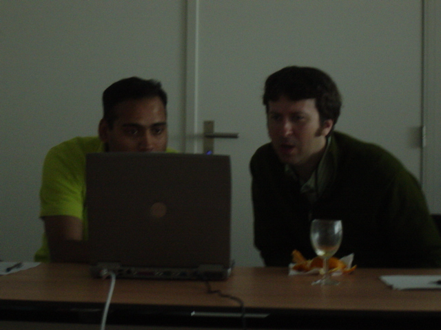 two men sitting at a desk with computers