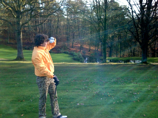 a young man standing in a park taking a picture of himself