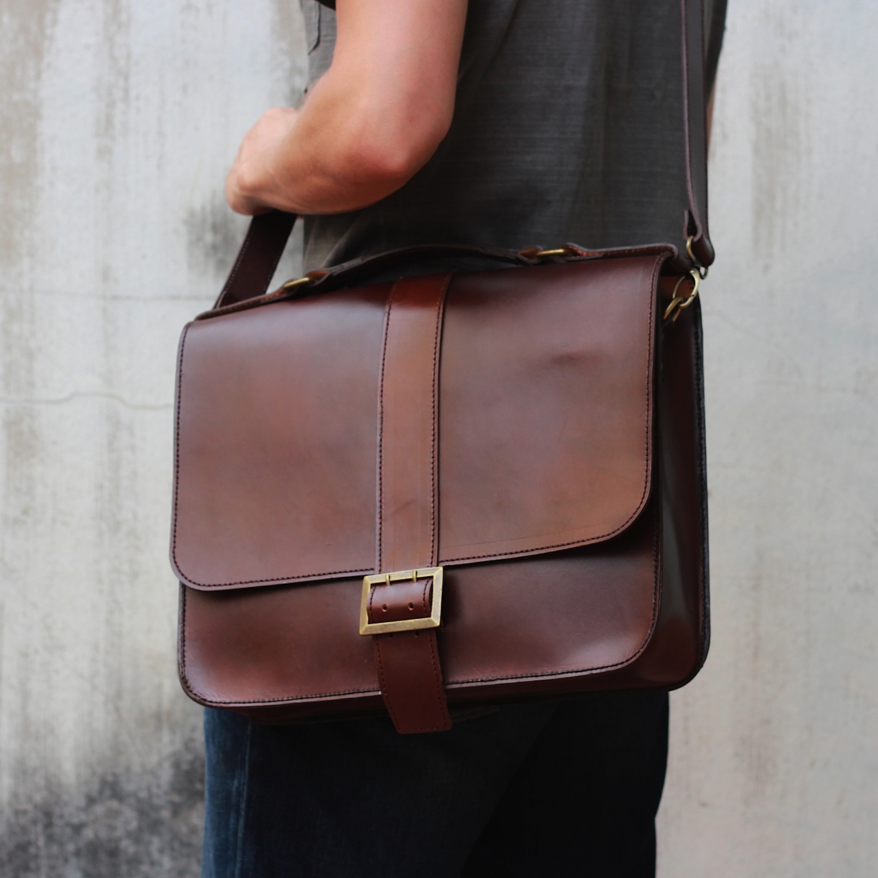 a man holding a leather bag, with one strap