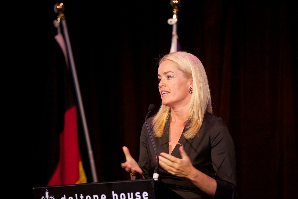 a woman is speaking at a podium on stage