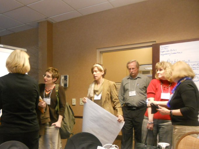 a group of people standing around talking in a conference room