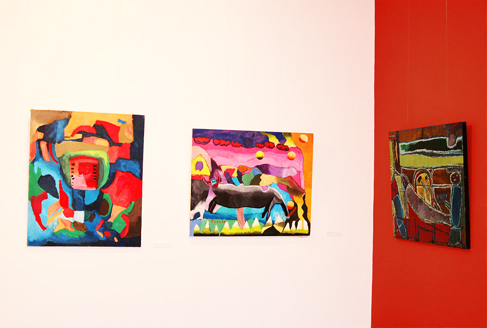 three colorful paintings hang on a white wall
