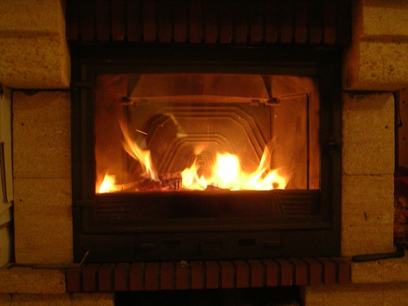 a fire burns brightly in a fireplace next to wood