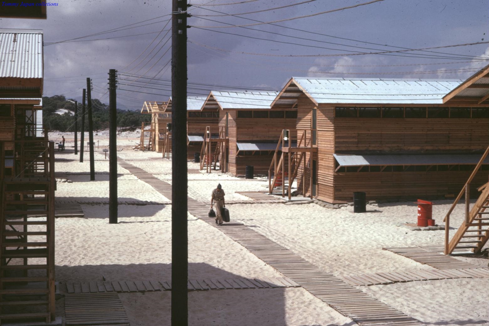 a man walks across a dirt road between two houses