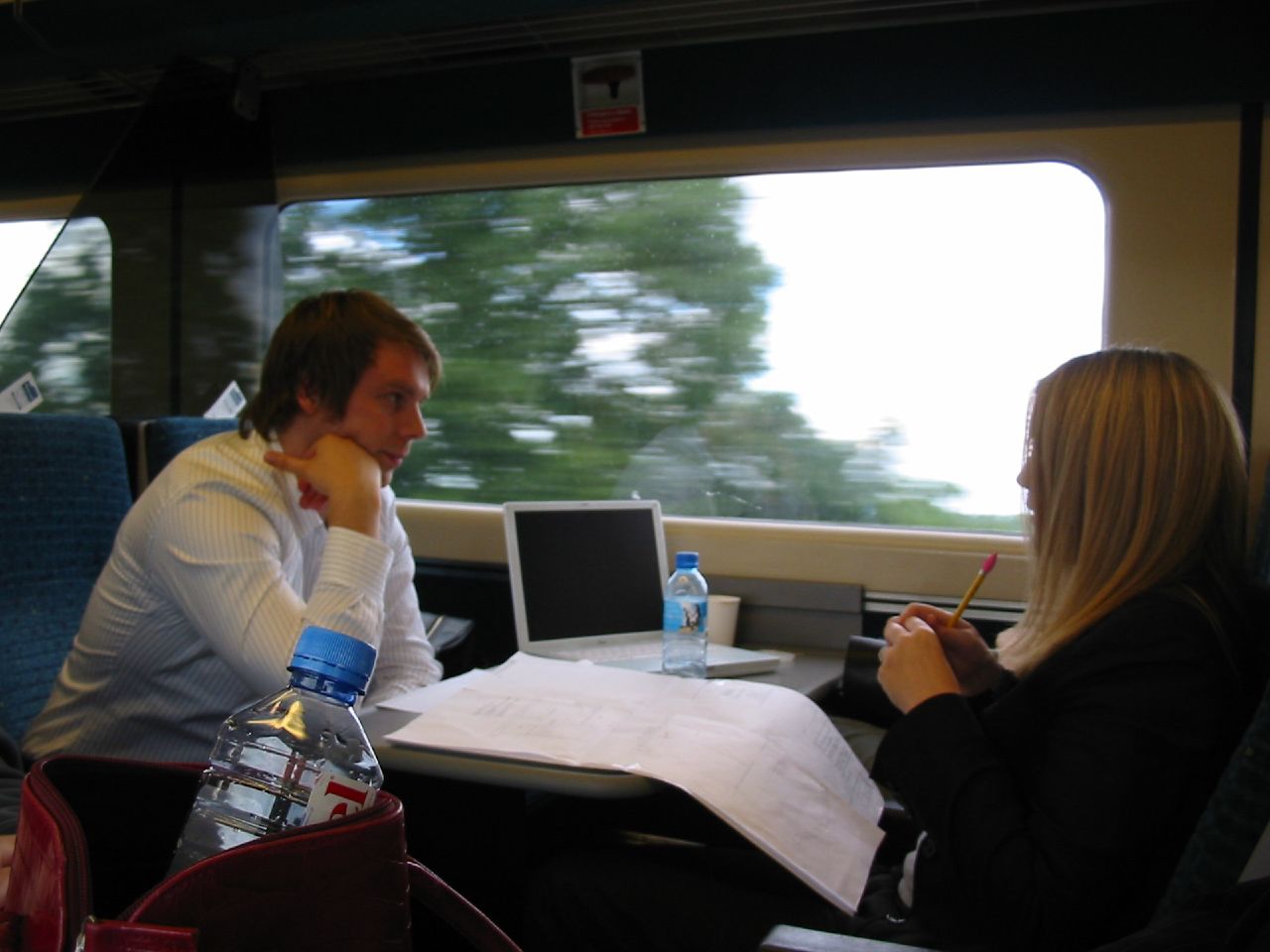 man and woman sitting on a train looking at papers
