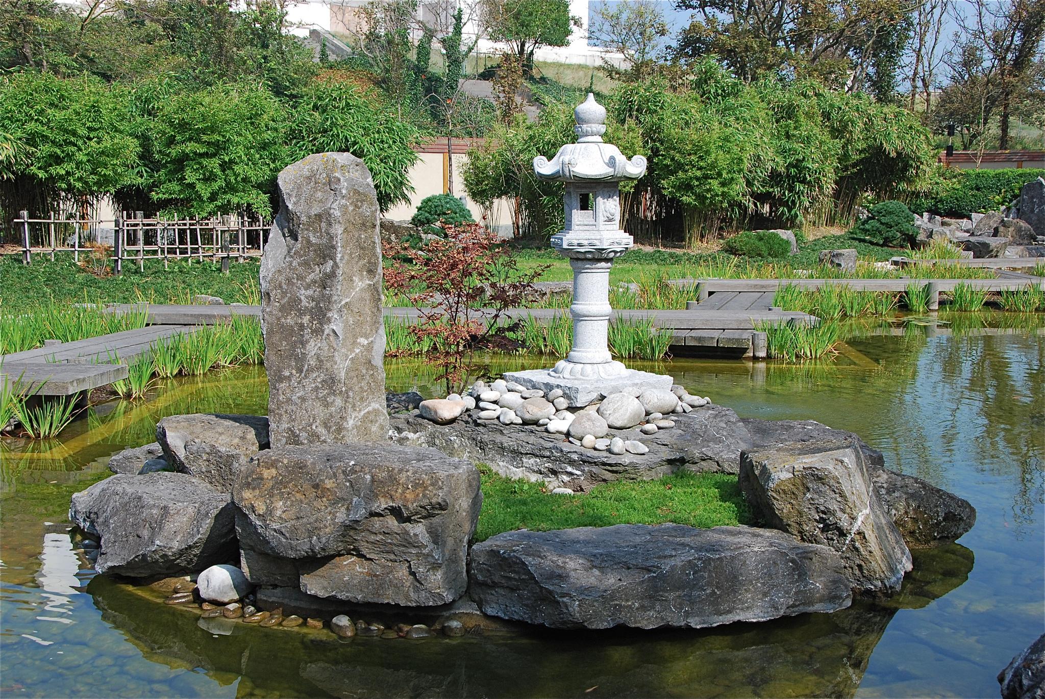 some rocks and an old water spout in a pond