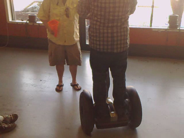 a boy and his grandfather ride a segway around a room