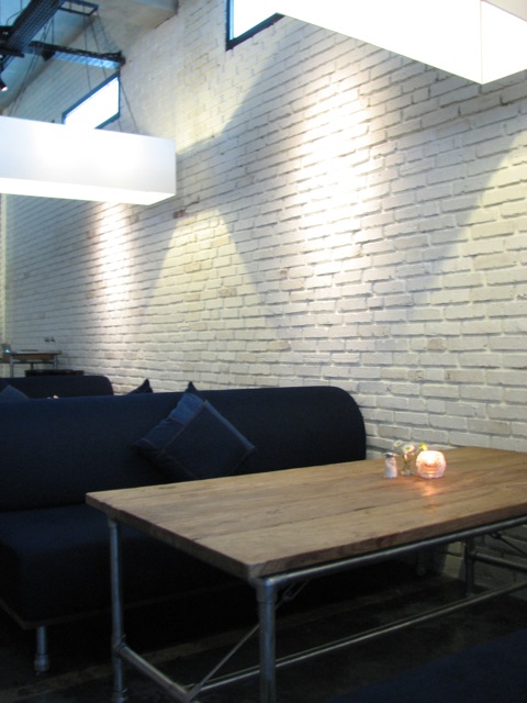 a living room with white brick walls and a blue couch