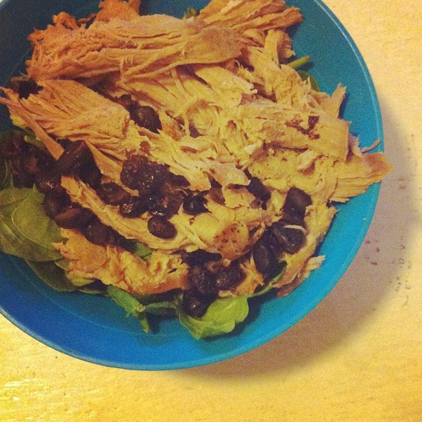 a blue bowl full of salad and meat with lettuce