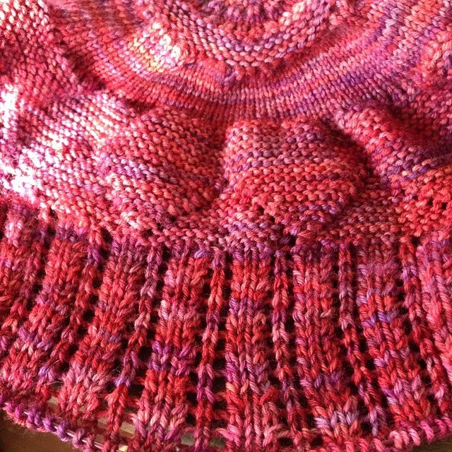 a hand knit pink hat sitting on top of a table