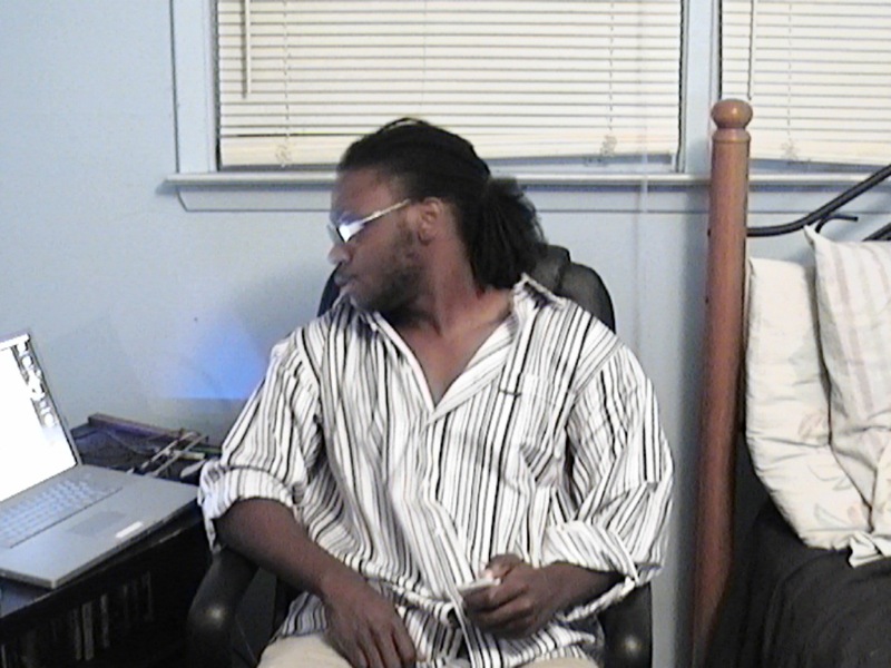 a man sitting in his chair, on the telephone with a laptop