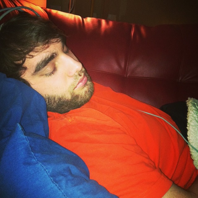 a man in an orange shirt is sleeping on a red couch