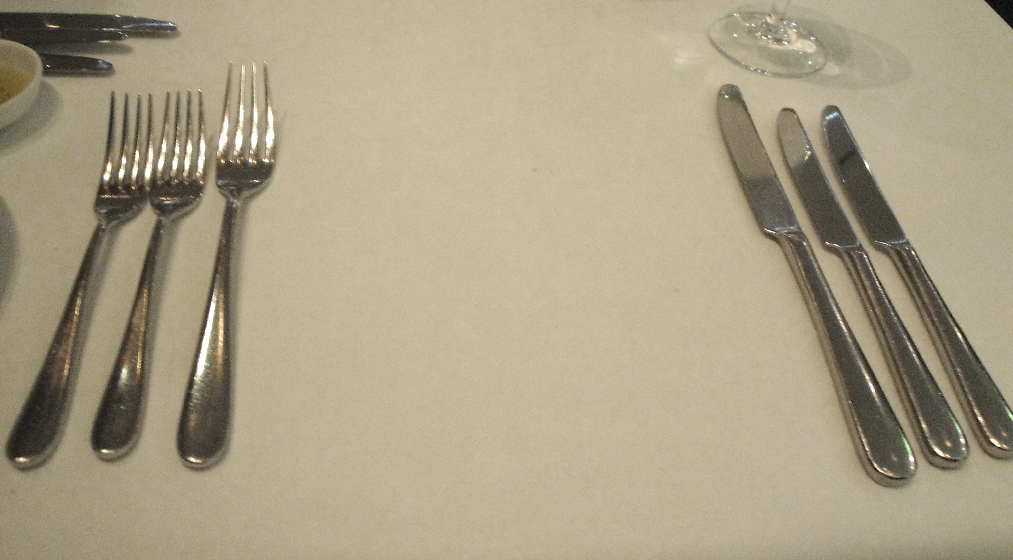 an arrangement of forks and spoons sits on a white table