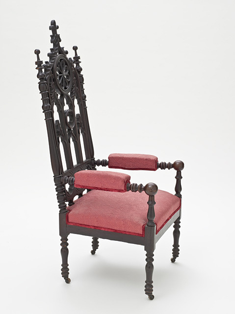 an upholstered armchair with red cushion, with cast iron frame, turned to the side