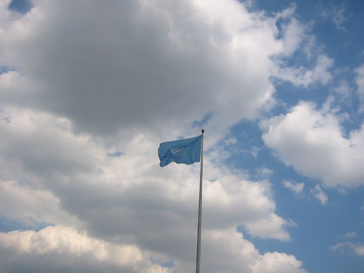 a flag flying in the wind under cloudy skies