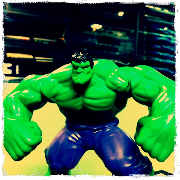a toy that is looking like hulk in front of a sign