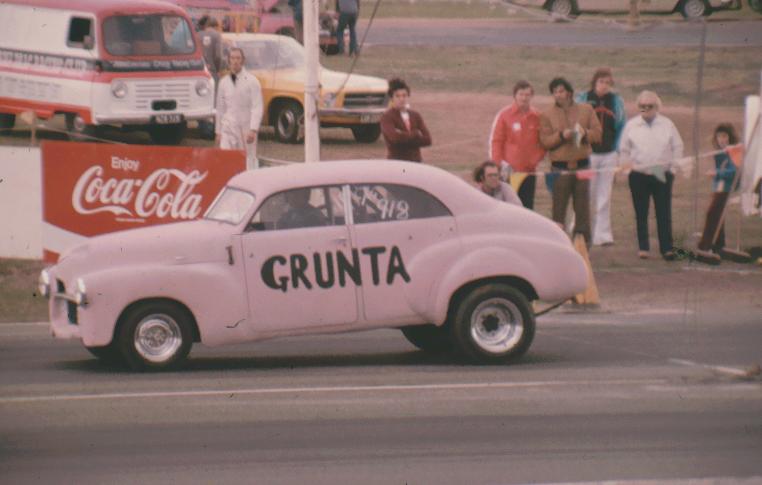 a pink old fashioned car with advertising on it
