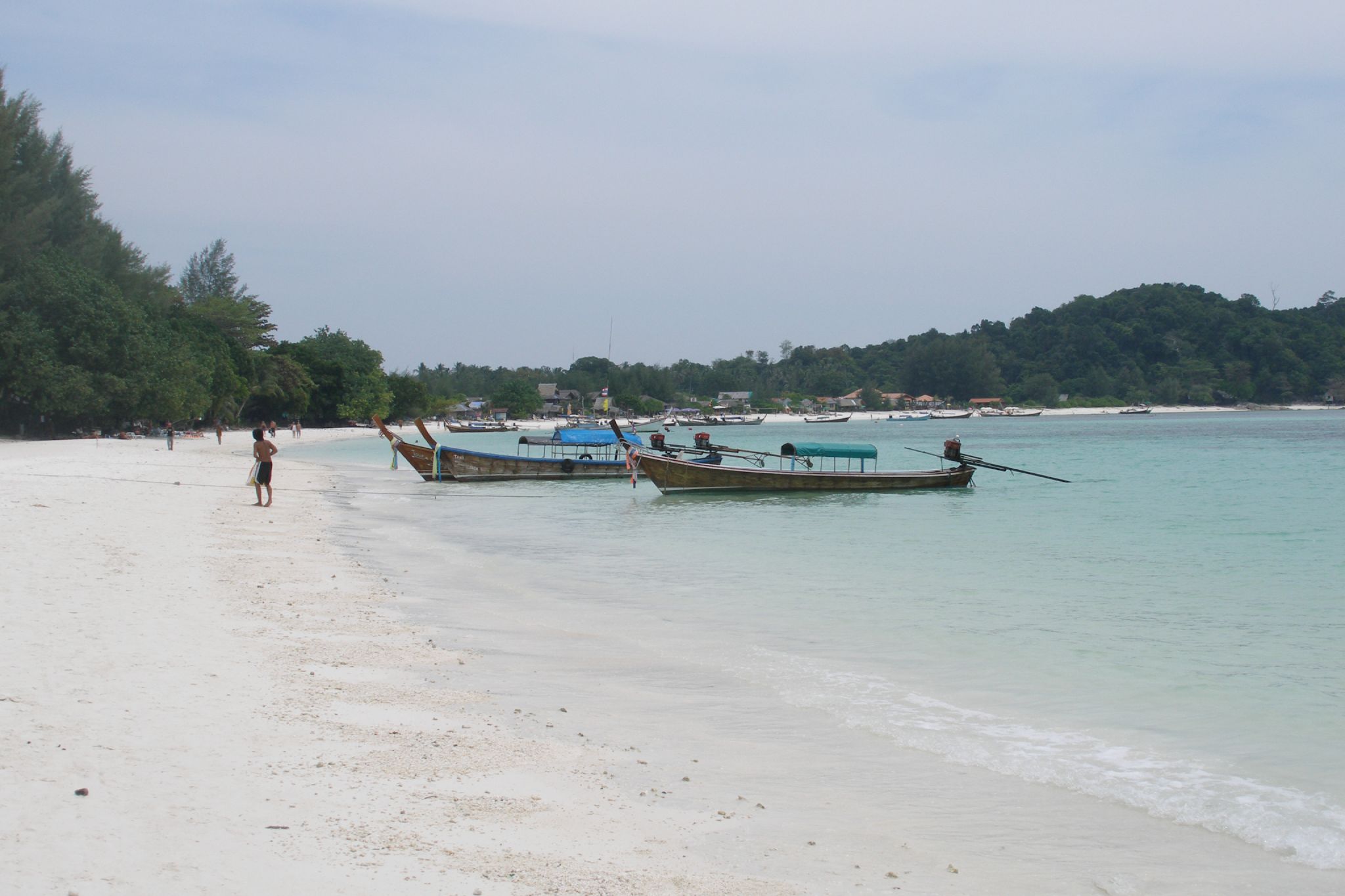 a white sandy beach with three boats in the water