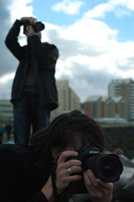 a man takes his po with a camera while another man looks into the distance