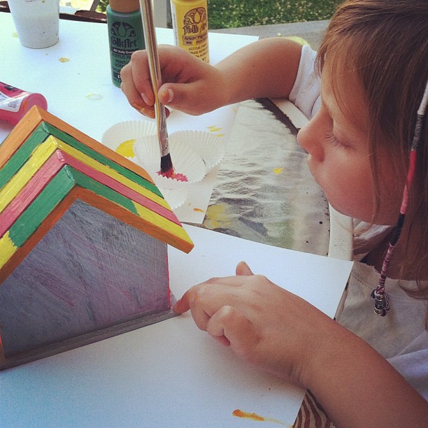 a girl painting a house out of some colored papers