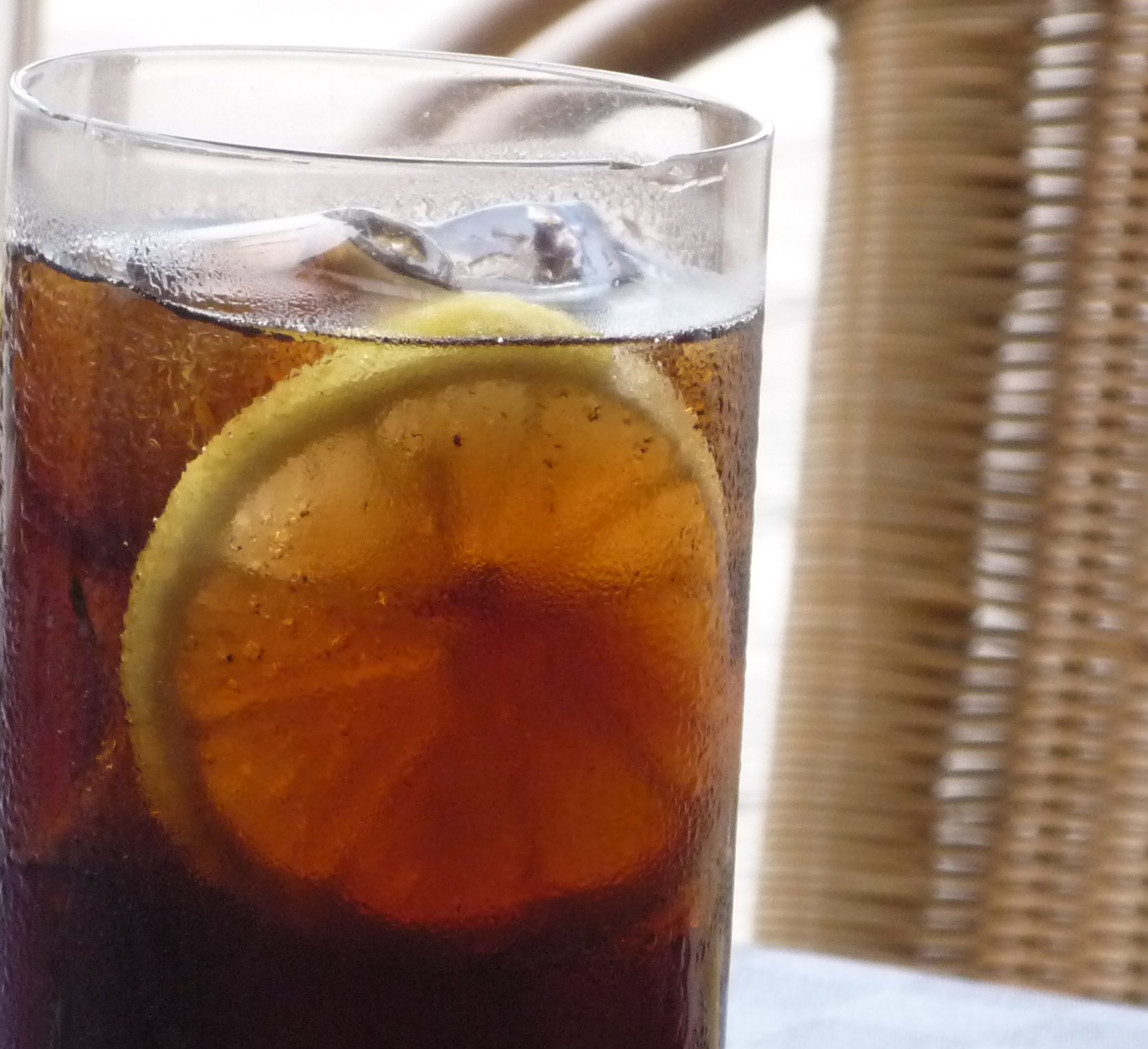 glass full of soda on a table outside