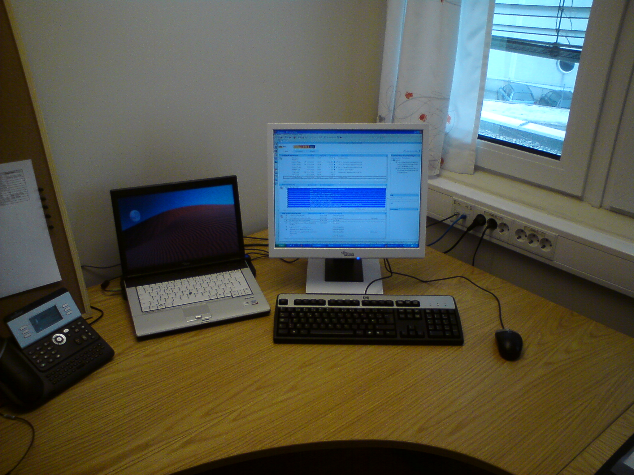 a desk with a keyboard, monitor, laptop, phone and computer monitor