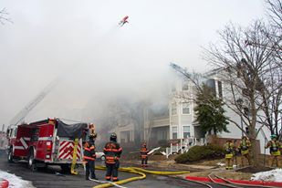 firefighters at scene of fire and ladders in a neighborhood