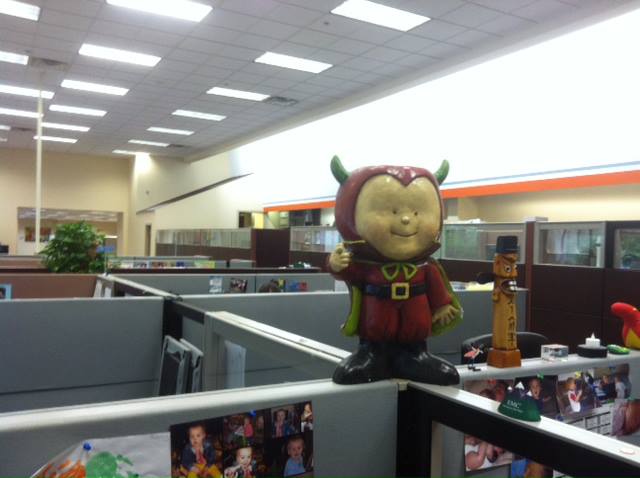 there is a giant toy doll in an office cubicle