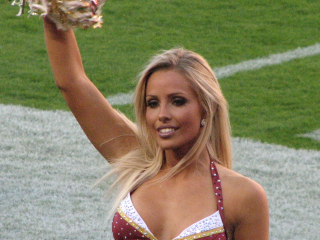  woman on field holding up white and maroon cheerleaders