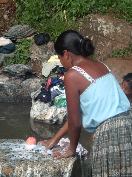 an image of woman washing clothes in a river