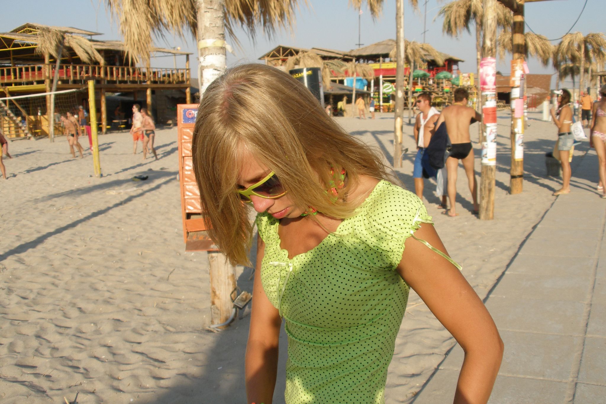 a girl with glasses on a beach by a palm tree