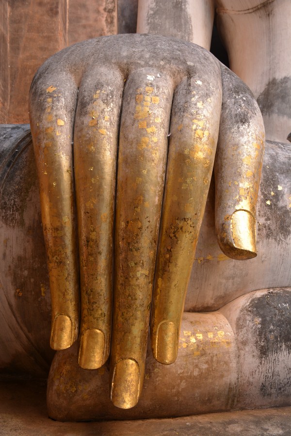 two statues of gold colored hands resting on the ground