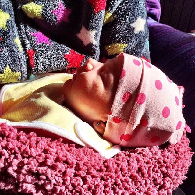a baby girl laying in a blanket and wearing a hat