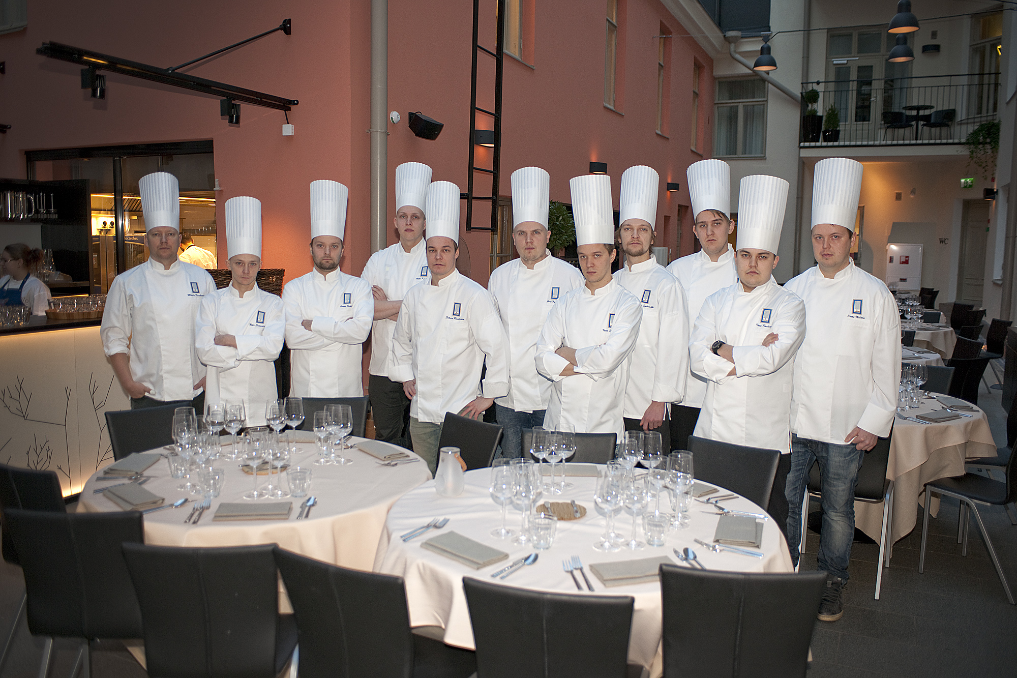 group of chefs posing in white uniforms with plates and glasses